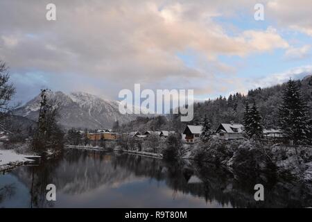 Les petites maisons au bord de la Rivière, montagnes de Neige et ciel panoramique à l'arrière-plan. Bad Goisern, Hallstatt, Autriche. Vue sur la rivière d'hiver. Banque D'Images