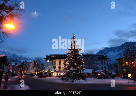 Bad Goisern, Hallstatt, Autriche. Vue de nuit sur l'arbre de Noël dans le centre. Les montagnes enneigées et la lune à l'arrière-plan. Banque D'Images