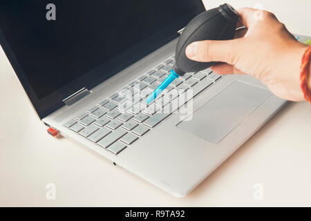 Coup de main de femme libre de balayer la poussière de clavier d'ordinateur portable à l'aide de l'ampoule de l'air. Banque D'Images