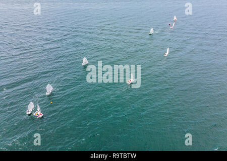 Drone aérien photo de jeunes adolescents sur de petits bateaux à voile en compétition dans la course à la mer émeraude de la Méditerranée Banque D'Images