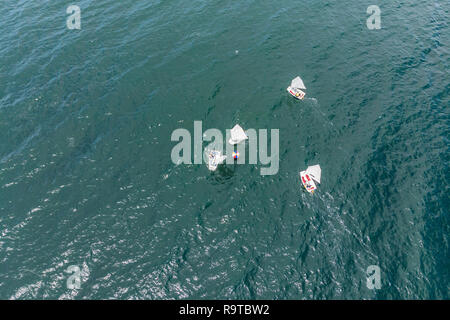 Drone aérien photo de jeunes adolescents sur de petits bateaux à voile en compétition dans la course à la mer émeraude de la Méditerranée Banque D'Images