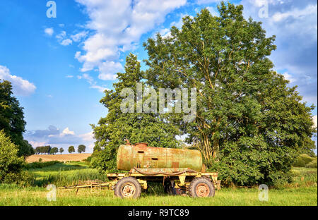 Old rusty metal réservoir d'eau sur remorque en face d'un grand arbre, pour le bétail au pâturage. Banque D'Images