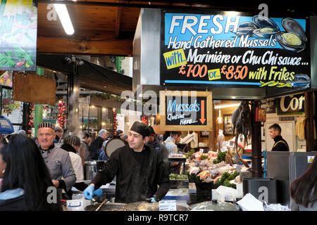 Vente de trader les moules fraîches cuites part recueilli sur un étal de fruits de mer du marché de l'arrondissement, dans le sud de Londres Angleterre Royaume-uni KATHY DEWITT Banque D'Images