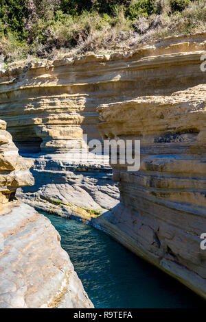 Printemps Ensoleillé vue de Love Canal ou Canal D'Amour avec l'eau bleu de la mer Ionienne et falaises stratifiées à Corfou, l'île de Corfou, Grèce Banque D'Images