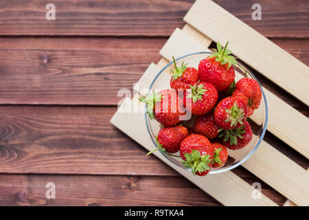 Tas de fraises dans un bol blanc sur fond de bois. Top view point. Banque D'Images