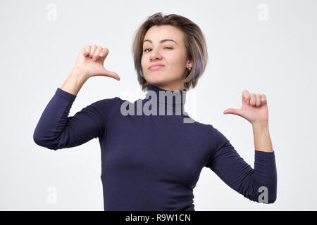 Femme à la confiance avec le sourire sur le visage, faisant elle-même avec les doigts d'être fier Banque D'Images