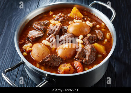 Close-up of Tcholent juive traditionnelle (Hamin) - plat principal pour le repas de Chabbat lent boeuf cuit avec des pommes de terre, les haricots et les œufs bruns dans un metal casserol Banque D'Images