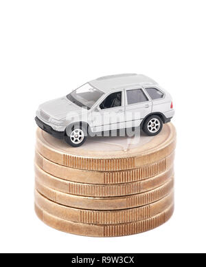 Petite voiture argent sur pile de pièces en euro isolé sur fond blanc Banque D'Images