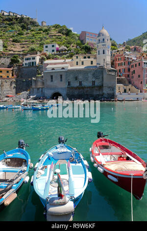 Bateaux de pêche ajouter de la couleur à Vernazza Harbour, l'un des cinq villages qui composent l'Italie célèbre Cinque Terre. Santa Margherita d'Antiochia en arrière-plan. Banque D'Images