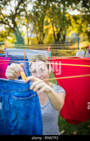 Jeune femme en mettant une corde à linge dans son jardin, en prenant bien soin de sa famille sur une base quotidienne Banque D'Images