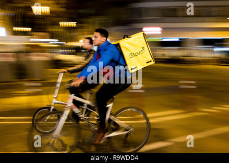 Barcelone, Espagne - 21 décembre 2018 : les jeunes coureurs travaillant pour Glovo riding bike service de livraison dans la ville la nuit. Livraison de nourriture joue un maire rol Banque D'Images