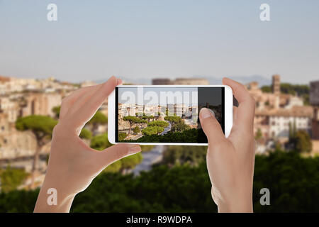 Un homme fait une photo de la ville de Rome colisée avec ciel bleu en été journée sur un téléphone mobile Banque D'Images