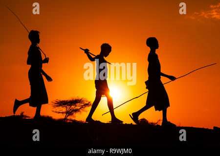 Tribu Hamar silhouettes au coucher du soleil à Labela village de vallée de l'Omo, Ethiopie Banque D'Images