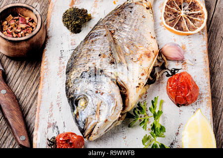 Dorado poisson au four avec des légumes sur une planche à découper Banque D'Images