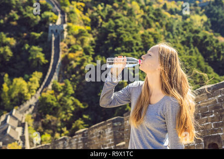 Joyeux joyeux joyeux femme touristiques à grande muraille de Chine l'eau potable sur voyage de vacances en Asie. En fille et le tourisme destination chinois Banque D'Images