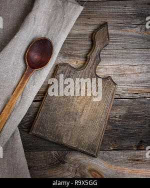 Ancienne cuillère en bois brun et découper sur un fond de bois, à côté d'un serviette gris, vue du dessus Banque D'Images