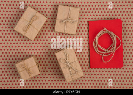 Concept de célébration - Coffrets cadeaux, rouge le bloc-notes, de la corde et de l'artisanat fait main décorative collection sur fond de papier de pois rouges Banque D'Images