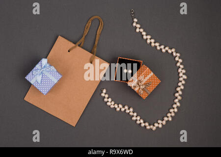 Concept de célébration - sac de cadeaux, coffrets cadeaux à pois blancs avec des bijoux de perle sur fond gris Banque D'Images