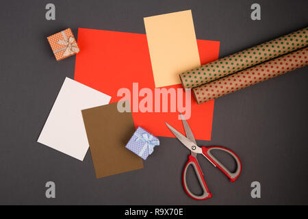 Concept de célébration - Coffrets cadeaux à pois blancs, d'emballage, papier couleur et ciseaux sur fond gris Banque D'Images