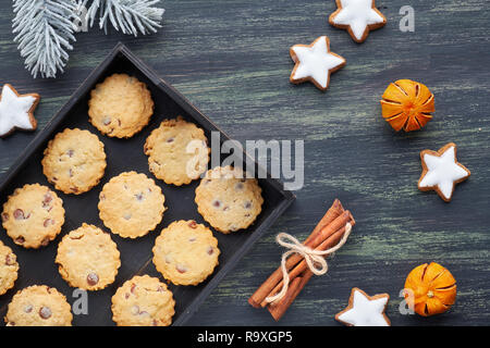 Cookies aux pépites de chocolat de Noël, mise à plat avec des épices et de l'hiver décorations sur bois rustique foncé Banque D'Images
