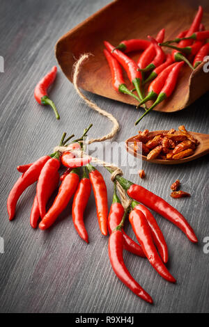Gros plan sur Red Hot Chili Peppers attaché avec une chaîne et une cuillère avec piments séchés sur fond de bois sombre. Arrière-plan de l'alimentation. Banque D'Images