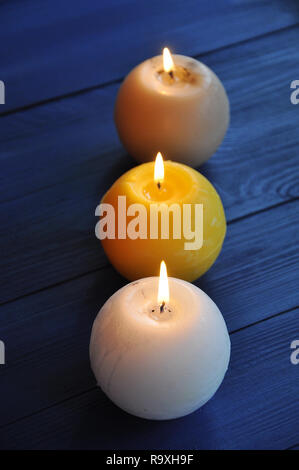 Blanc, jaune et beige paraffine bougies sphériques sur la table en bois bleu. Selective focus Banque D'Images
