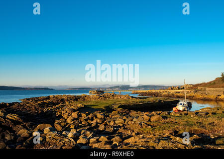 En regardant la Rocky Harbour à l'ancienne jetée à Portencross dans Seamill West Kilbride par une froide nuit de Noël en Ecosse au coucher du soleil. Banque D'Images