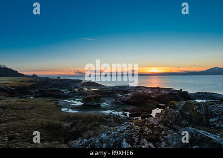 En regardant la Rocky Harbour à l'ancienne jetée à Portencross dans Seamill West Kilbride sur un coucher de soleil froid la veille de Noël en Ecosse. Banque D'Images