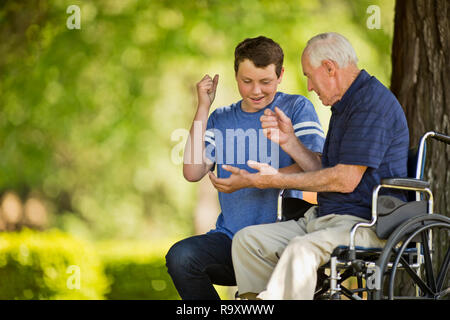 Smiling teenage boy playing pierre papier ciseaux avec son grand-père. Banque D'Images