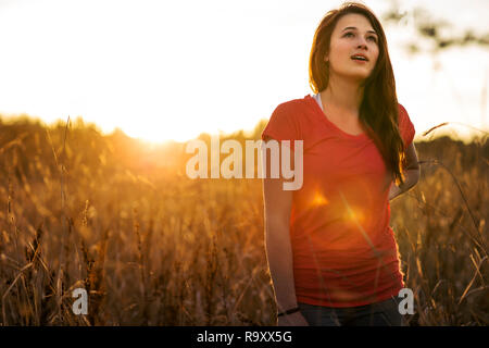 Souriante jeune femme prend une pause dans sa campagne courir à la fin de l'après-midi du soleil. Banque D'Images