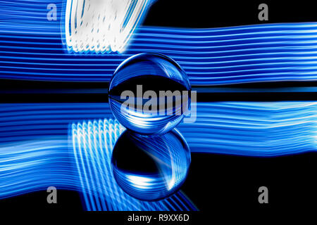 Light painting avec une lentille ball / Crystal Ball / bille de verre / sphère avec rayures bleu coloré réflexions sur surface noire. Banque D'Images