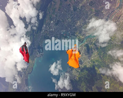 Ces deux pilotes sont wingsuit s'amuser ensemble en volant en une formation autour des nuages. Ils sourient à chaque autre et profiter de l'heure dans le ciel. Banque D'Images