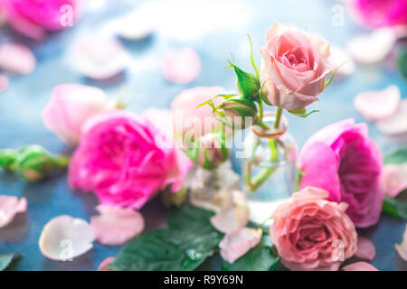 Bouteilles en verre avec pivoine rose roses sur un fond clair avec l'exemplaire de l'espace. Coupe féminine de pétales et de fleurs dans des tons pastel Banque D'Images