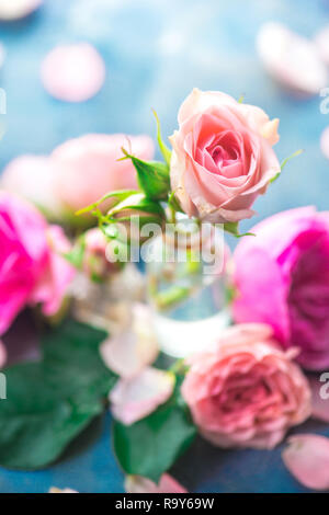 Roses roses dans de petites bouteilles en verre sur un fond gris neutre avec l'exemplaire de l'espace. Un concept féminin de pétales et de fleurs dans des tons pastel Banque D'Images