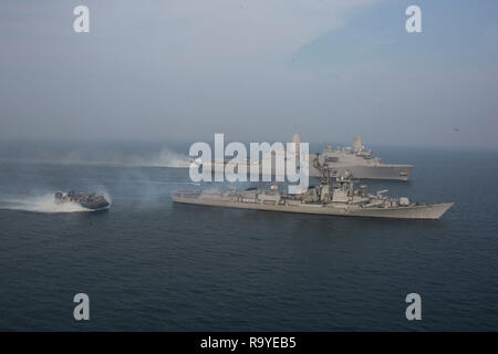 Un débarquement de la Marine américaine, manœuvres à coussin d'air aux côtés de la marine indienne destroyer INS Rajput, bas, la voile en collaboration avec la U.S. Navy San Antonio-classe de transport amphibie USS dock Anchorage, haut, au cours des exercices de coopération, le 26 décembre 2018 dans l'Océan Indien. Banque D'Images