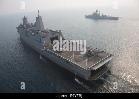 La Marine américaine San Antonio-classe de transport amphibie USS dock Anchorage navigue avec un marine indienne UH-3H hélicoptère sur le pont d'atterrissage lors des exercices de coopération avec la marine indienne destroyer INS Rajput, droit, 26 décembre 2018 dans l'Océan Indien. Banque D'Images
