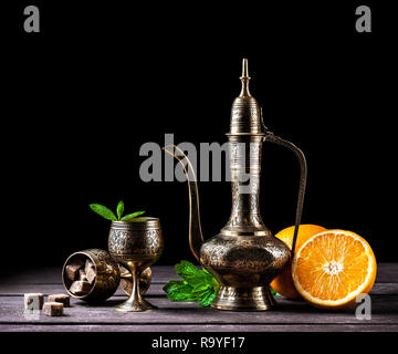 Thé marocain à la menthe et des oranges dans oriental cooper pot et tasses sur fond de bois rustique Banque D'Images