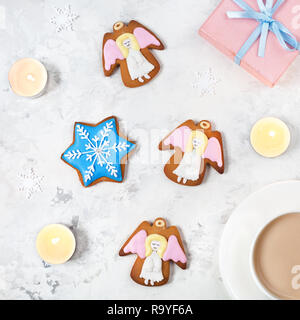 Angels cookies, boîte cadeau et tasse de café près de bougies sur fond blanc Banque D'Images