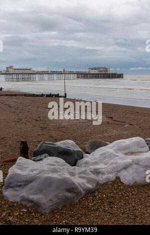 La plage de galets et la jetée victorienne de Worthing, West Sussex, lors d'une journée d'hivers nuageux avec rochers. Banque D'Images