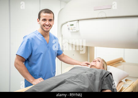 Technicien de laboratoire mâle femme seniro aider après l'IRM en laboratoire hospitalier. Young caucasian doctor examining vieille femme pour examen médical en clinique. Peop Banque D'Images