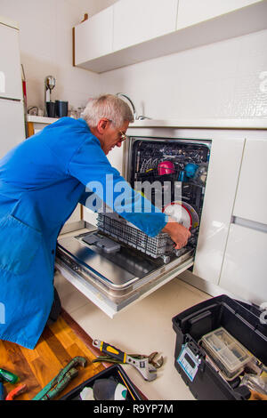 Plumbe en uniforme bleu de la fixation des appareils ménagers dans la maison Banque D'Images