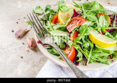 Detox de source fraîche salade mélange avec des légumes (concombre, citron, tomates, roquette, jeunes épinards), et sur la lumière de l'ardoise, de la pierre ou du béton. Top v Banque D'Images