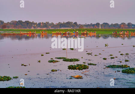 Le soir brumeux sur le lac Taungthaman, banque verte de Amarapura est vue sur arrière-plan, bateaux traditionnels en bois flottant à l'U Bein bridge to watch Banque D'Images