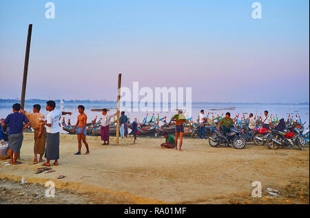 MANDALAY, MYANMAR - février 21, 2018 : le soir sur la rive de lac Taungthaman, pêcheurs et plaisanciers birmans jouent chinlone (caneball) - g populaire Banque D'Images