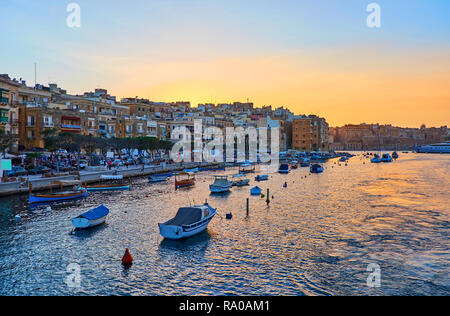 Le lumineux Ciel de coucher du soleil se reflète dans les eaux de Vittoriosa marina et voyants les vieux quartiers de Sliema, Malte. Banque D'Images