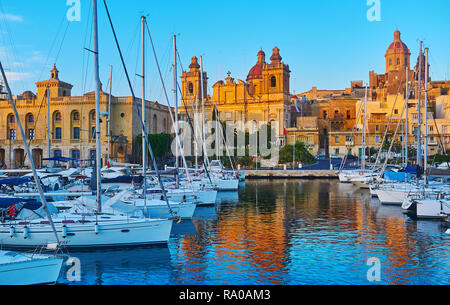 Les rayons de soleil illuminent les édifices médiévaux et des églises le long de Vittoriosa Marina avec des yachts et bateaux amarrés, balancement sur les douces vagues, Sengl Banque D'Images