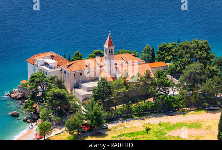 Voir de belle baie avec plage et monastère dominicain de la ville de Bol, Île de Brac, Croatie. Monastère dominicain dans Bol, construit au 15e siècle. Remorquage de bol Banque D'Images