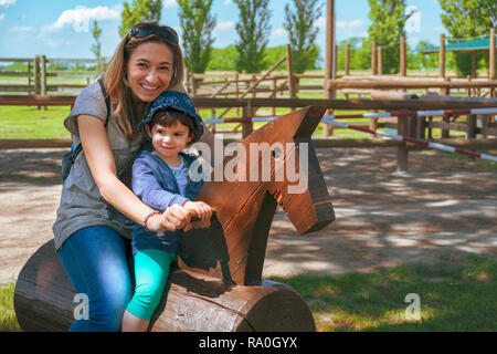 Famille heureuse horse ranch zoo fond voyage mère et bébé enfant ride Banque D'Images