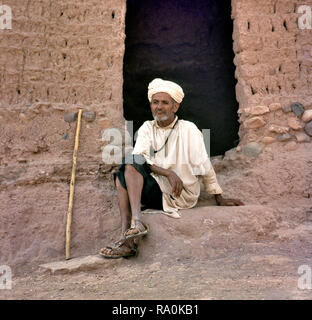 Ksar Ait Benhaddou, Morocco-August 12, 2017 : l'homme se reposant à l'extérieur entrée d'une petite maison dans le village. C'est un vieux village berbère en brique adobe o Banque D'Images