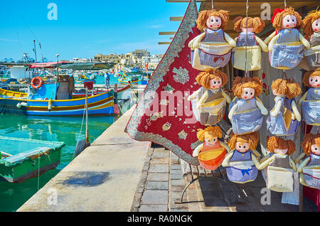 Boutique Textile des poupées pour cuisine, nappes et serviettes brodées, situé sur la rive paisible du port de pêche de Marsaxlokk, marché touristique, Banque D'Images